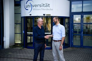 Zwei Männer stehen vor dem Hauptgebäude der UW/H.