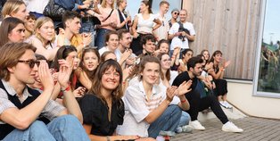 Sommerfest 2025 Lachende und klatschende Mensche sitzen auf einer Treppe.