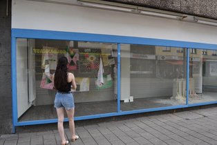 Young woman looking at art exhibition from outside. 