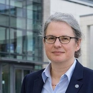 Eine Frau steht vor einem Gebäude.