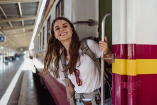 Frau, die lächelnd aus der Tür eines Zugs schaut