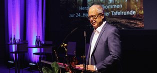 Ein Mann steht vor einem Rednerpult auf einer Bühne.