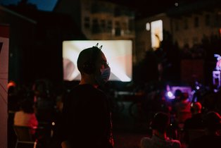 Spectator with mask and headphones in front of screen. 