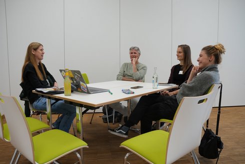 Four people sit around a table and talk to each other.