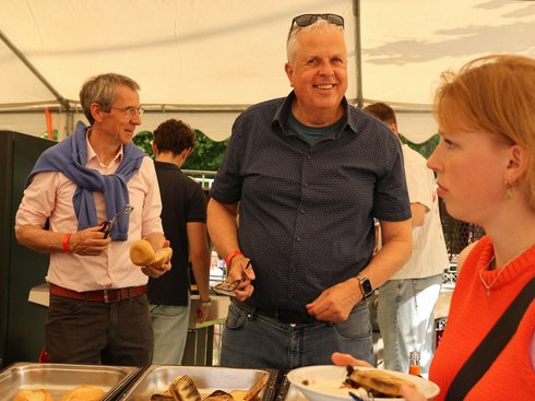 Zwei Männer bedienen an einem Bratwurststand.